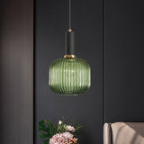 Green ribbed pendant lit on a dark wall above cut flowers