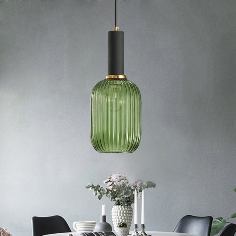 Green ribbed pendant lit on a concrete wall above dried flowers