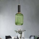 Green ribbed pendant lit on a concrete wall above dried flowers