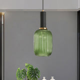 Green ribbed pendant lit on a grey wall beside a leafy plant