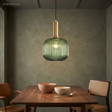 Green ribbed pendant lit above a dining table on a green wall