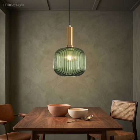 Green ribbed pendant lit above a dining table on a green wall