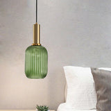 Green ribbed pendant lit above a bed piled with pale pillows