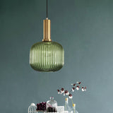 Green ribbed oval pendant lit on a green wall beside a decanter
