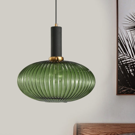 Green ribbed oval pendant lit on a pale wall beside a palm frond