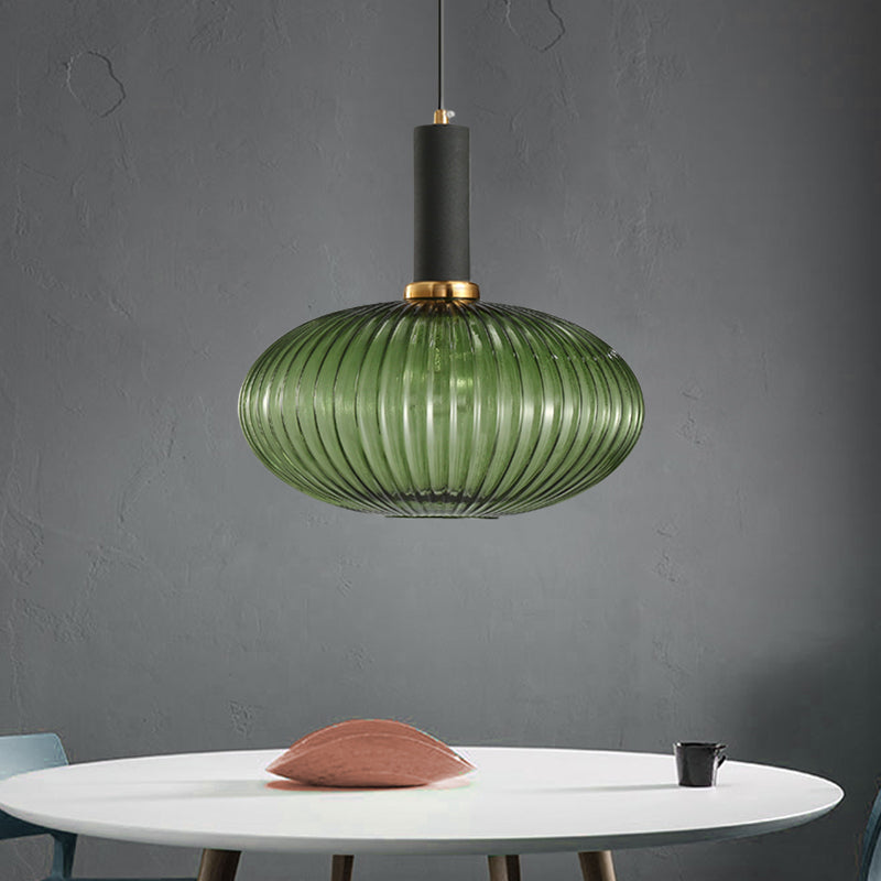 Green ribbed oval pendant lit on a grey wall above a white table