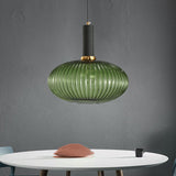 Green ribbed oval pendant lit on a grey wall above a white table