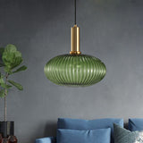 Green ribbed oval pendant lit on a grey wall by a blue sofa