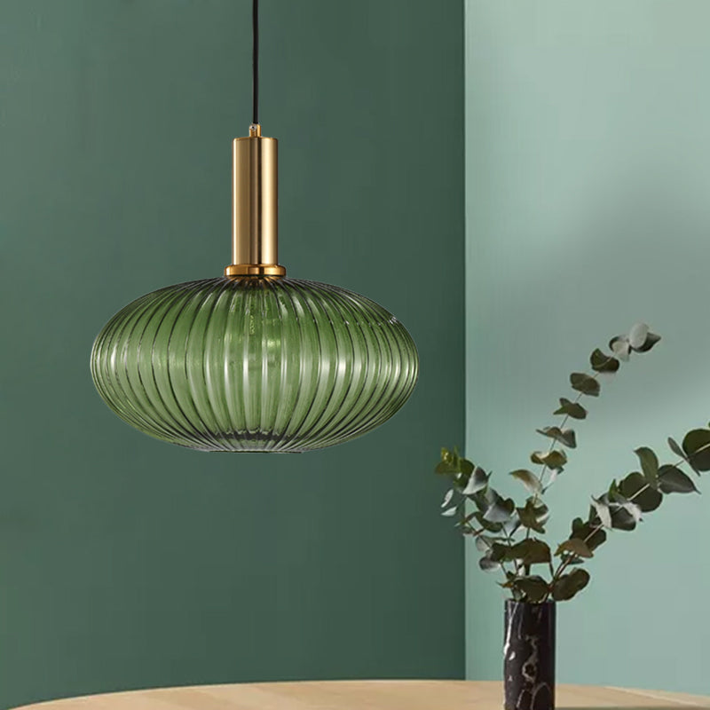 Green ribbed oval pendant lit on a green wall with eucalyptus