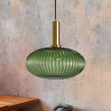 Green ribbed oval pendant lit against a mottled pink plaster wall