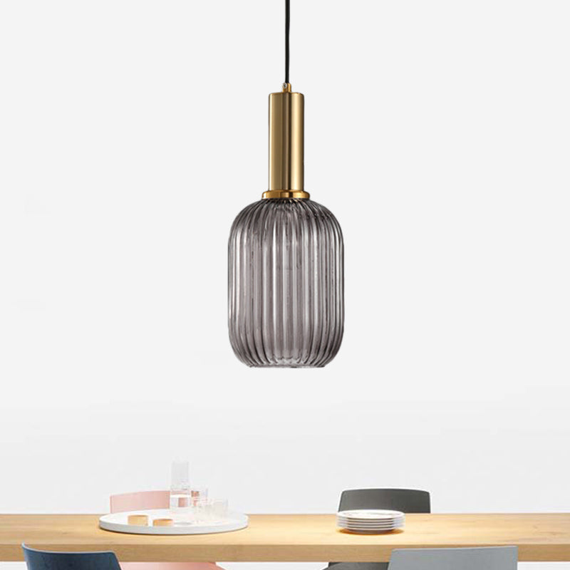 Smoke ribbed capsule pendant lit above a pale timber table
