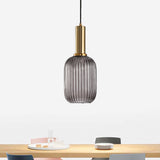 Smoke ribbed capsule pendant lit above a pale timber table