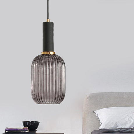 Smoke ribbed pendant lit beside a bed and a dark bedside table