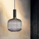 Smoke ribbed pendant lit warm against a dark textured wall