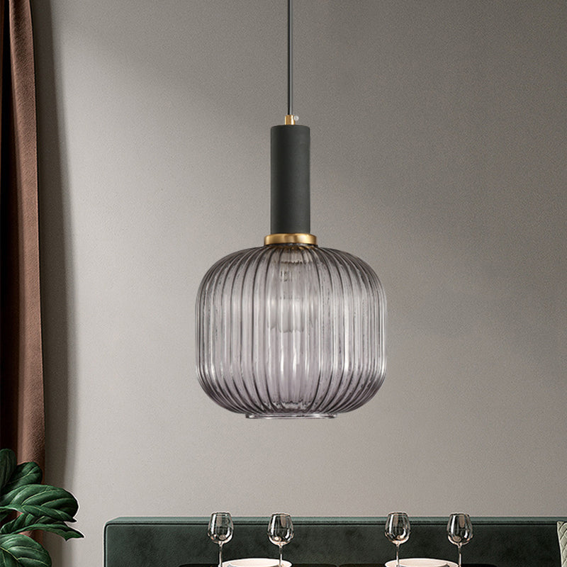 Smoke ribbed pendant lit above a dining table by a green sofa
