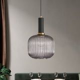 Smoke ribbed pendant lit above a dining table by a green sofa