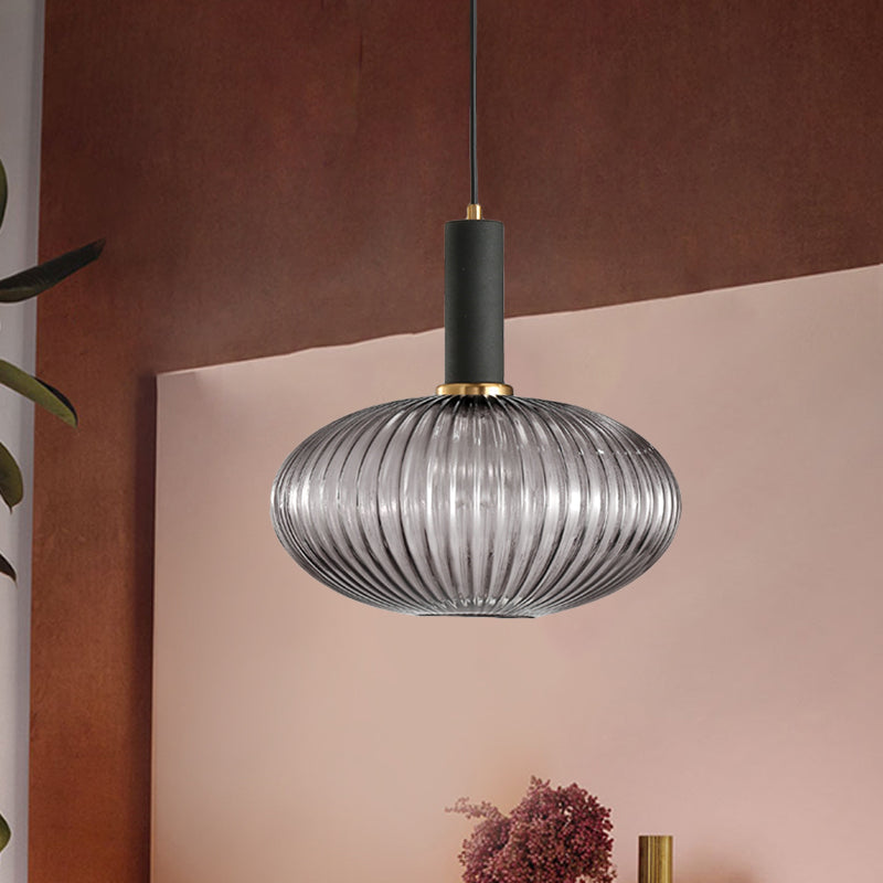 Smoke ribbed pendant lit against a pink and rust painted wall