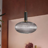 Smoke ribbed pendant lit against a pink and rust painted wall