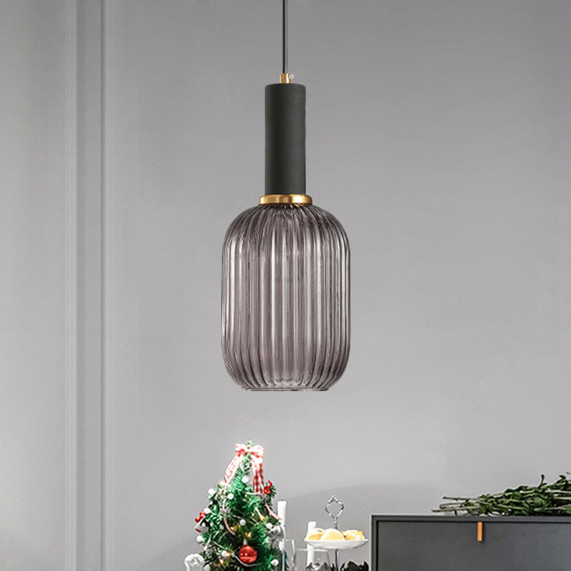 Smoke ribbed pendant lit on a white wall beside a Christmas tree