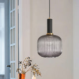 Smoke ribbed pendant lit by a window beside dried flower stems