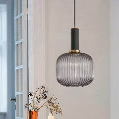 Smoke ribbed pendant lit by a window beside dried flower stems