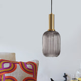 Smoke ribbed pendant lit in a pale room above a bright cushion
