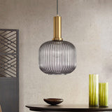 Smoke ribbed pendant lit on concrete beside tall green vases