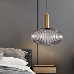 Smoke ribbed pendant lit beside a grey bed and a brass lamp