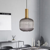 Smoke ribbed pendant lit above a bench in a grey kitchen