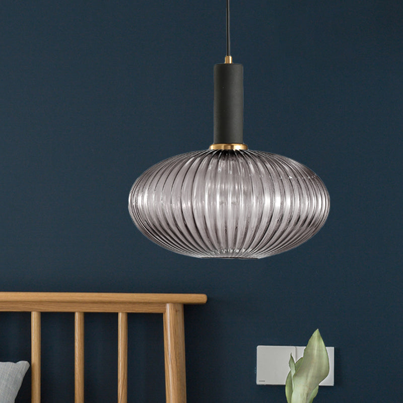 Smoke ribbed oval pendant lit against a deep blue painted wall