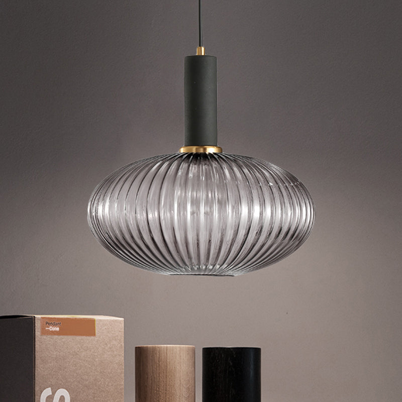 Smoke ribbed oval pendant lit above books on a grey backdrop