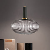 Smoke ribbed oval pendant lit above books on a grey backdrop