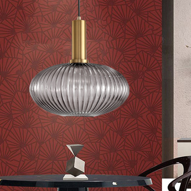 Smoke ribbed oval pendant lit against a red patterned wall