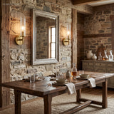 Two brass tube sconces on stone walling above a rustic dining table