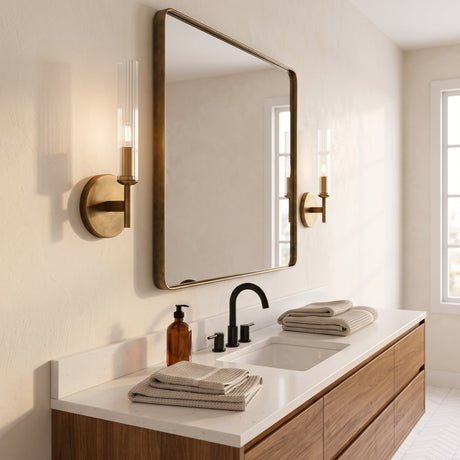 Two brass ribbed glass tube sconces flanking a bathroom vanity mirror