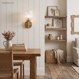 Single fluted glass sconce beside a mirror on white panelling