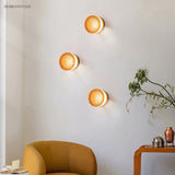 Three amber ribbed wall lights above a mustard armchair in a living room