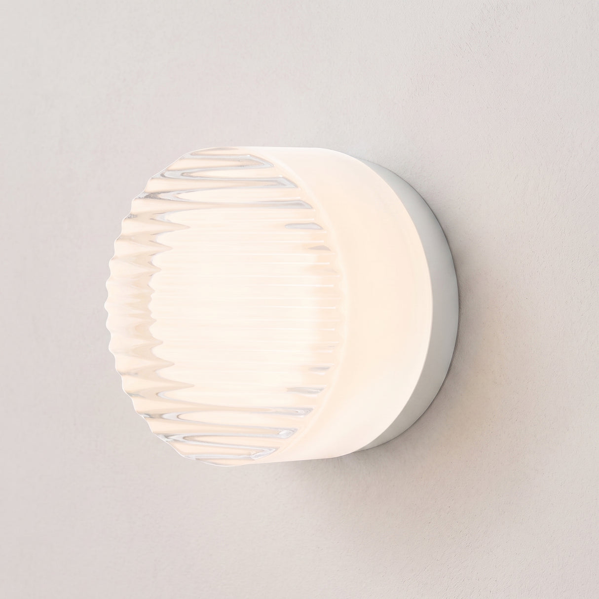 Round ribbed acrylic LED wall light in white on a plain wall