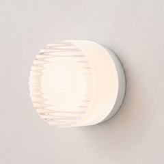 Round ribbed acrylic LED wall light in white on a plain wall