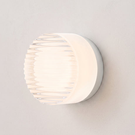 Round ribbed acrylic LED wall light in white on a plain wall