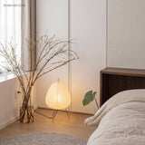 Rice paper table lamp glowing in a bedroom corner beside dried branches