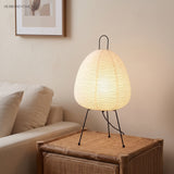 Rice paper table lamp on a rattan side table beside a linen sofa
