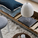 Rice paper table lamp on a low bench with floor cushions and a rug
