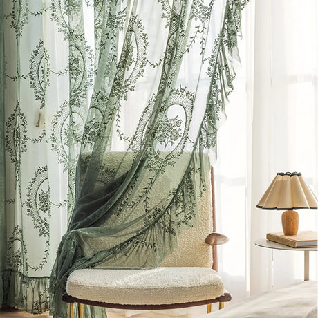 Rod-pocket top design for easy installation of dark green floral embroidered sheer curtains with ruffle detail.