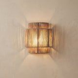 Woven rope wall lamp lit against a plain plaster wall