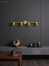 Brass spotlight bar with four heads lit on a dark panelled wall above a table