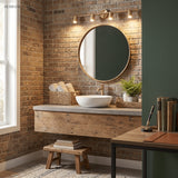 Brass spotlight bar lit above a round mirror on an exposed brick bathroom wall