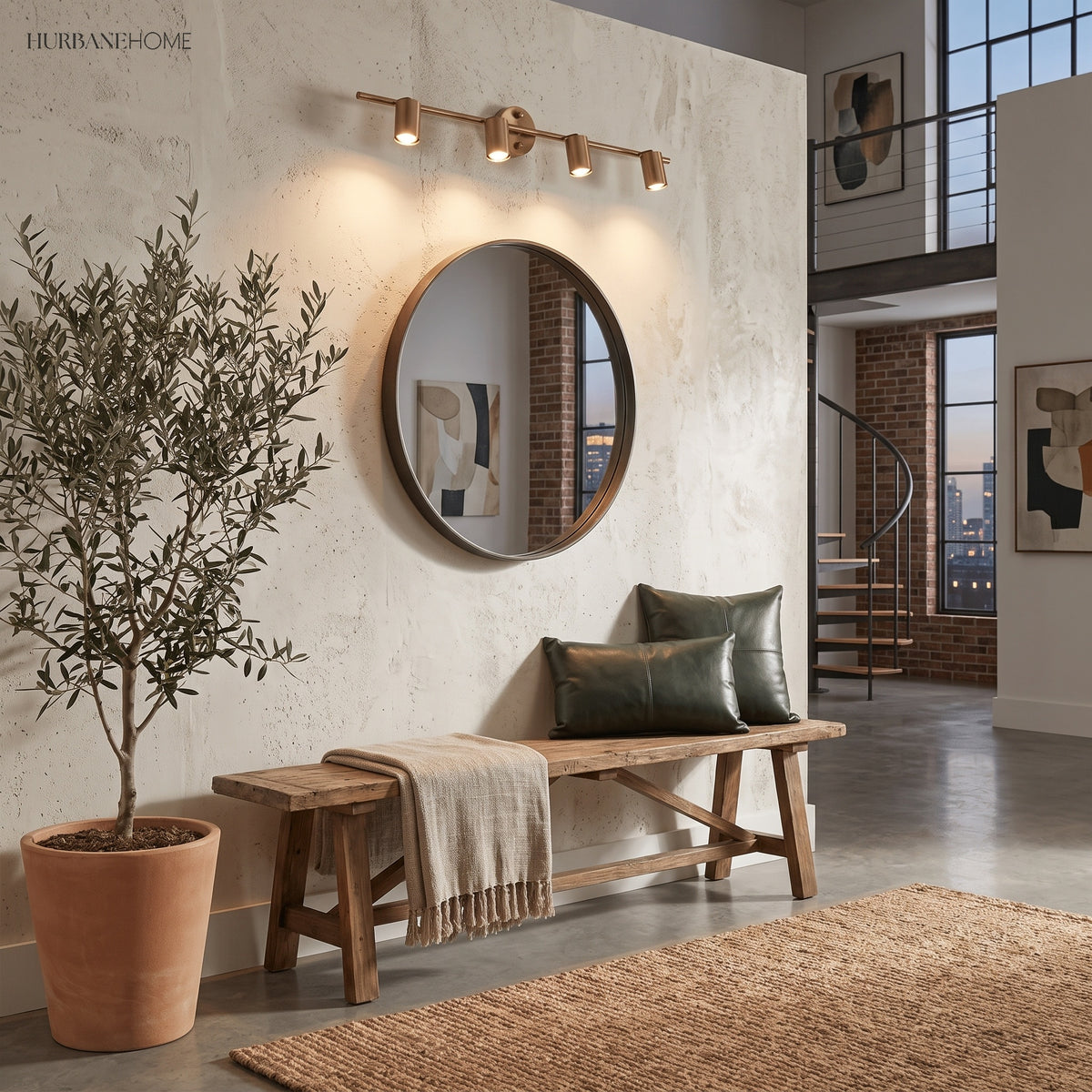 Brass spotlight bar lit above a round mirror and bench in a plaster hallway