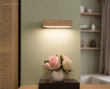 Pale oak sconce glowing above a console table with pink roses