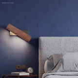 Walnut bar sconce lit against a deep blue bedroom wall